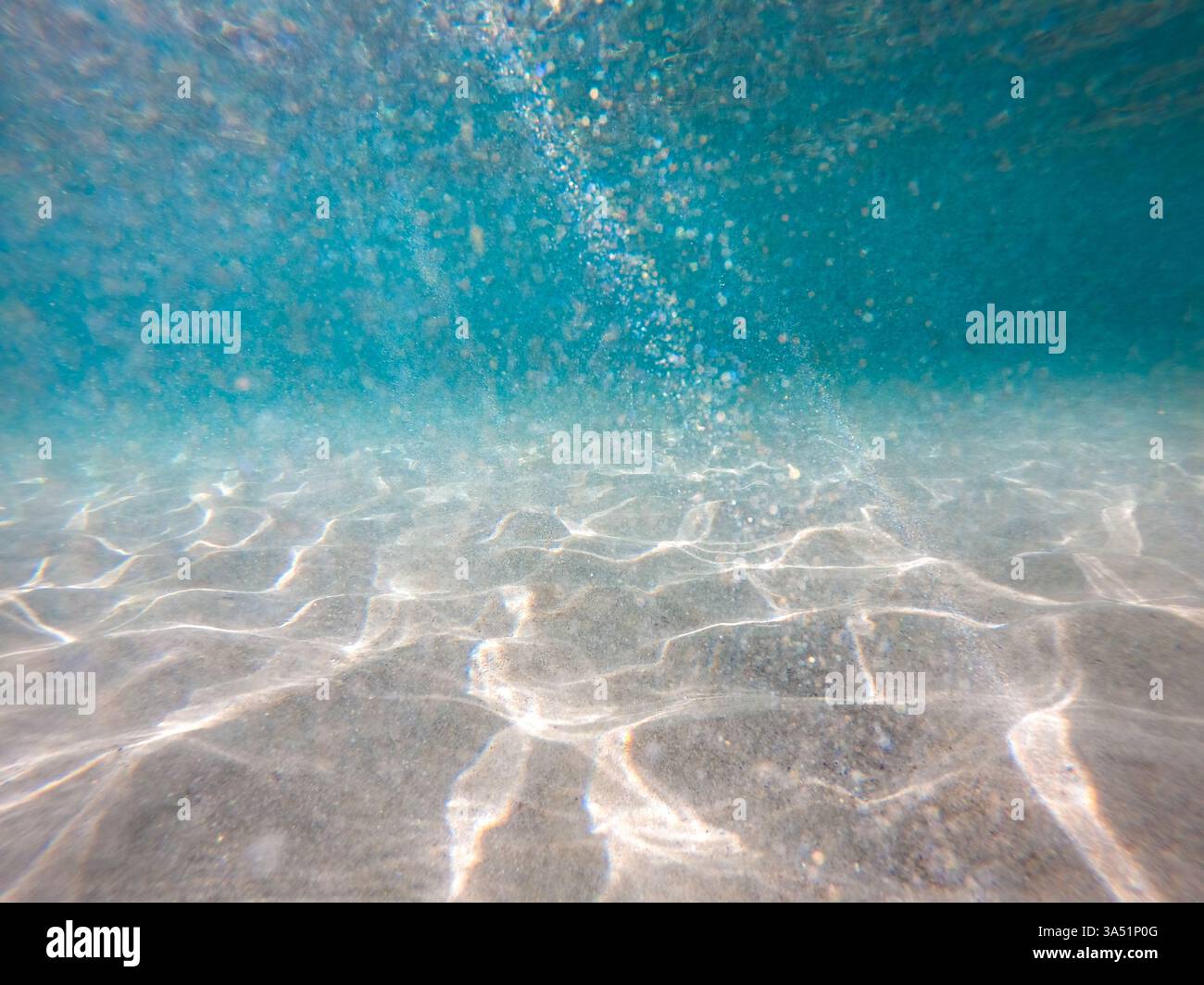 Le acque cristalline e turchesi circondano la sabbia bianca su una spiaggia tropicale con i raggi del sole che affettano l'acqua. Questa tranquilla scena costiera cattura le coste paradisiache ed è ideale per viaggi e vacanze in Asia, tra cui Filippine, Palawan ed El Nido. Foto Stock