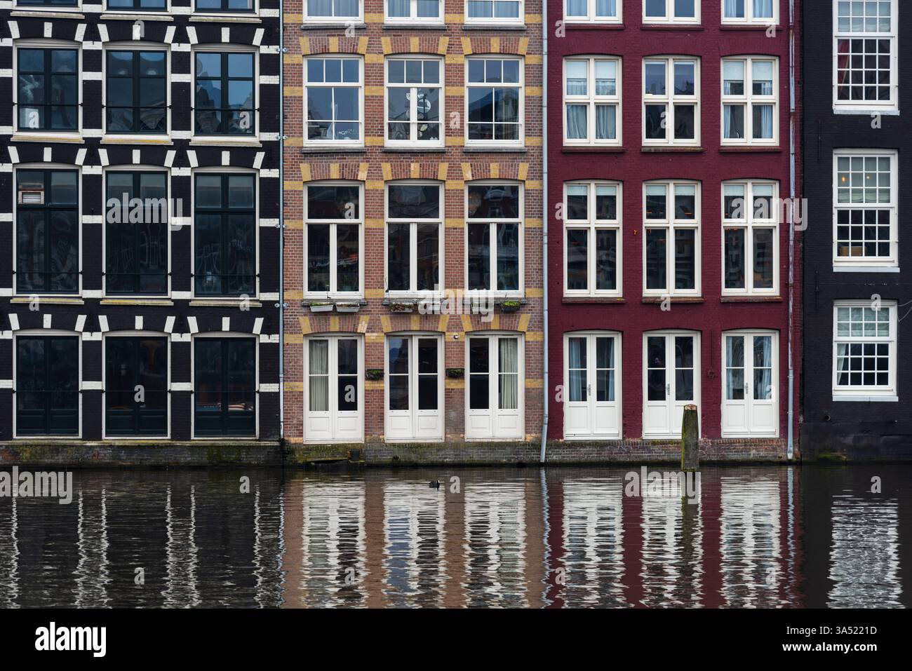 Case colorate e storte che si riflettono su un canale di amsterdam, paesi bassi, creando una scena pittoresca Foto Stock