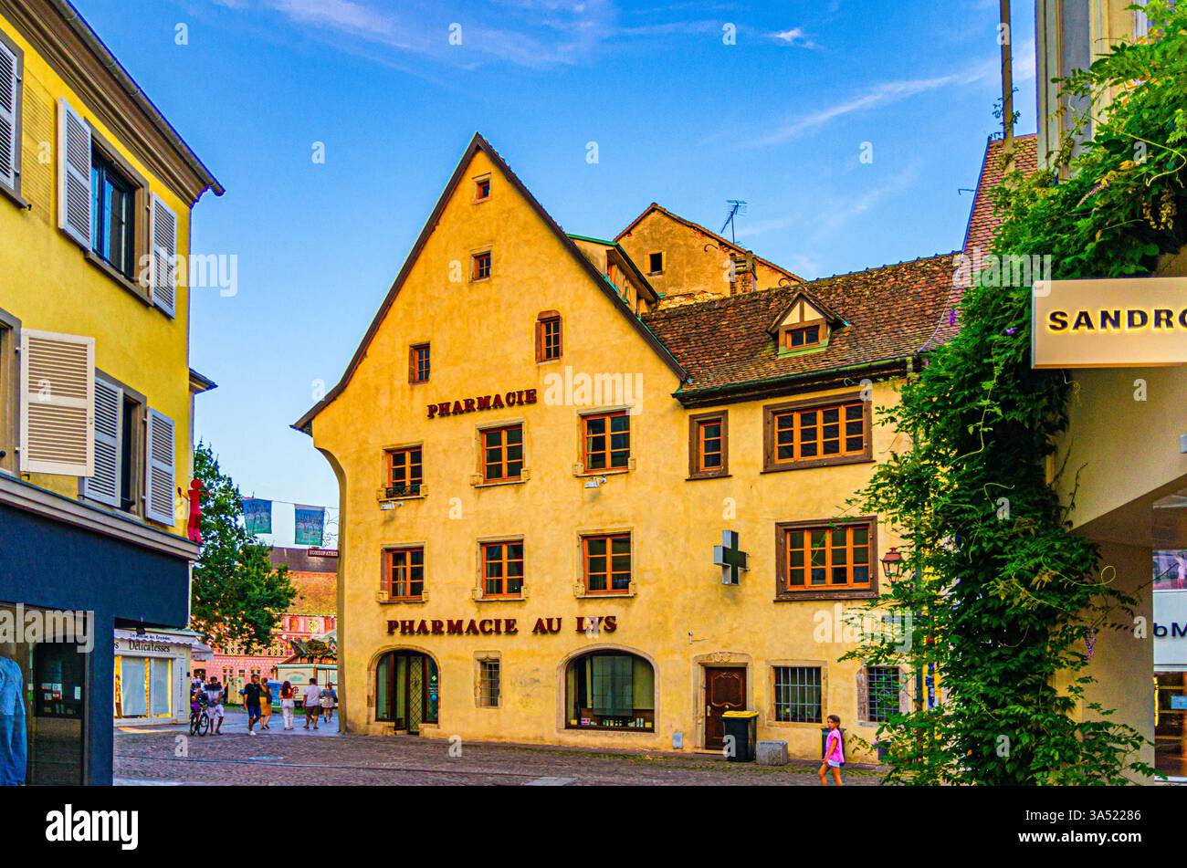 Mulhouse, Francia, 10 luglio 2024: Vecchie case colorate Farmacia Aux Lys Zielinski edificio su una piccola piazza pedonale nella città vecchia Mulhouse città storica Foto Stock