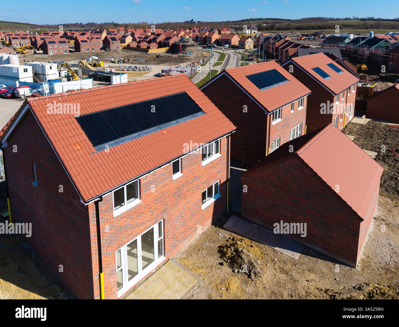 I tetti di una fila di case di nuova costruzione in un cantiere con tetto integrato o pannelli solari integrati nel tetto per un'energia economica e sostenibile in un ambiente ecologico Foto Stock