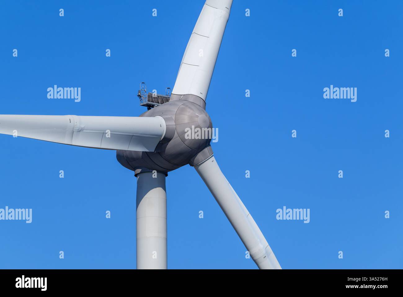 Primo piano della turbina eolica che mostra la torre, la navicella e le enormi pale del rotore contro il cielo blu Foto Stock