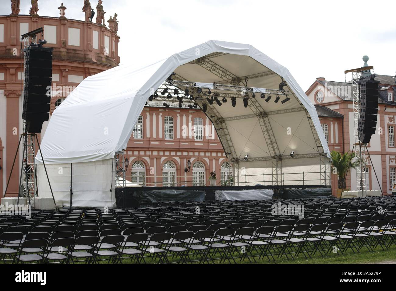 Wiesbaden, Germania - 14 luglio 2016: Un palco da concerto allestito con file di posti per un concerto di musica classica nei giardini del palazzo con il Palazzo Biebrich in th Foto Stock