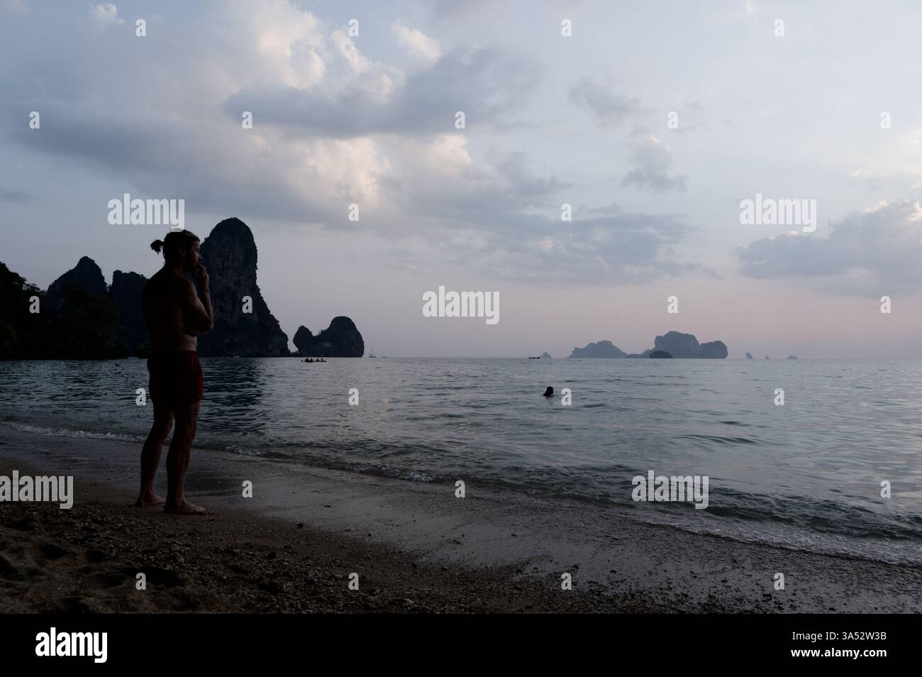 Un uomo guarda all'orizzonte sul Tonsai, mentre il crepuscolo si deposita sul Mare delle Andamane Foto Stock