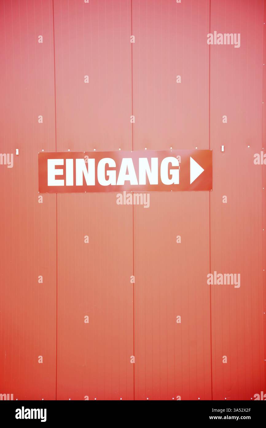 Un cartello d'ingresso rosso rettangolare con scritta bianca su una facciata in metallo rosso brillante Foto Stock
