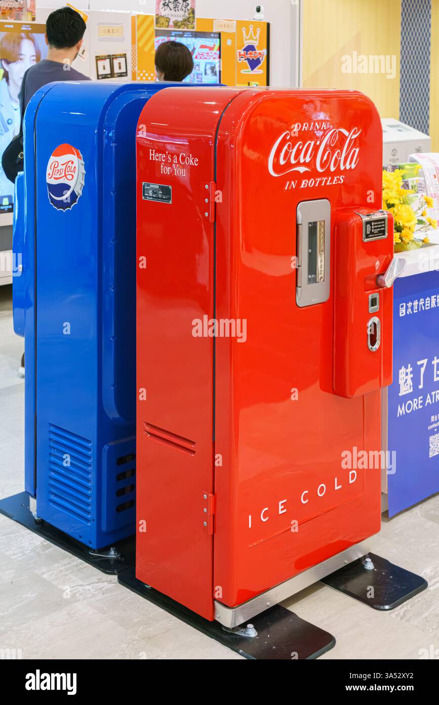 Osaka, Giappone - settembre 25 2024, verticale, Una vista ravvicinata di due antiche macchine per bibite gassate, blu e rosse, Coca-Cola e Pepsi-Cola, in un centro commerciale Foto Stock