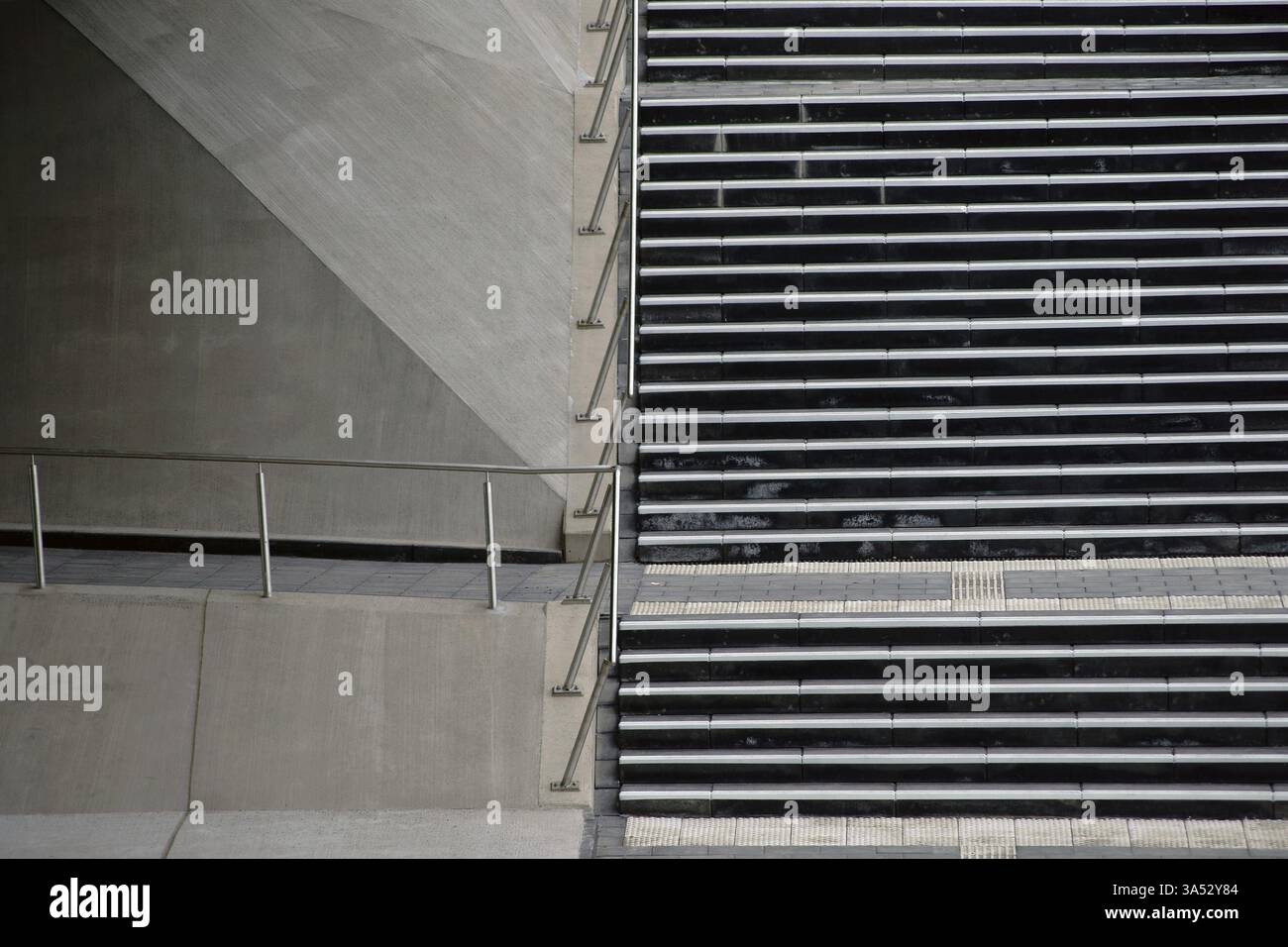 Una scala con una ringhiera in acciaio inossidabile conduce lungo il lato verso un ponte della metropolitana Foto Stock
