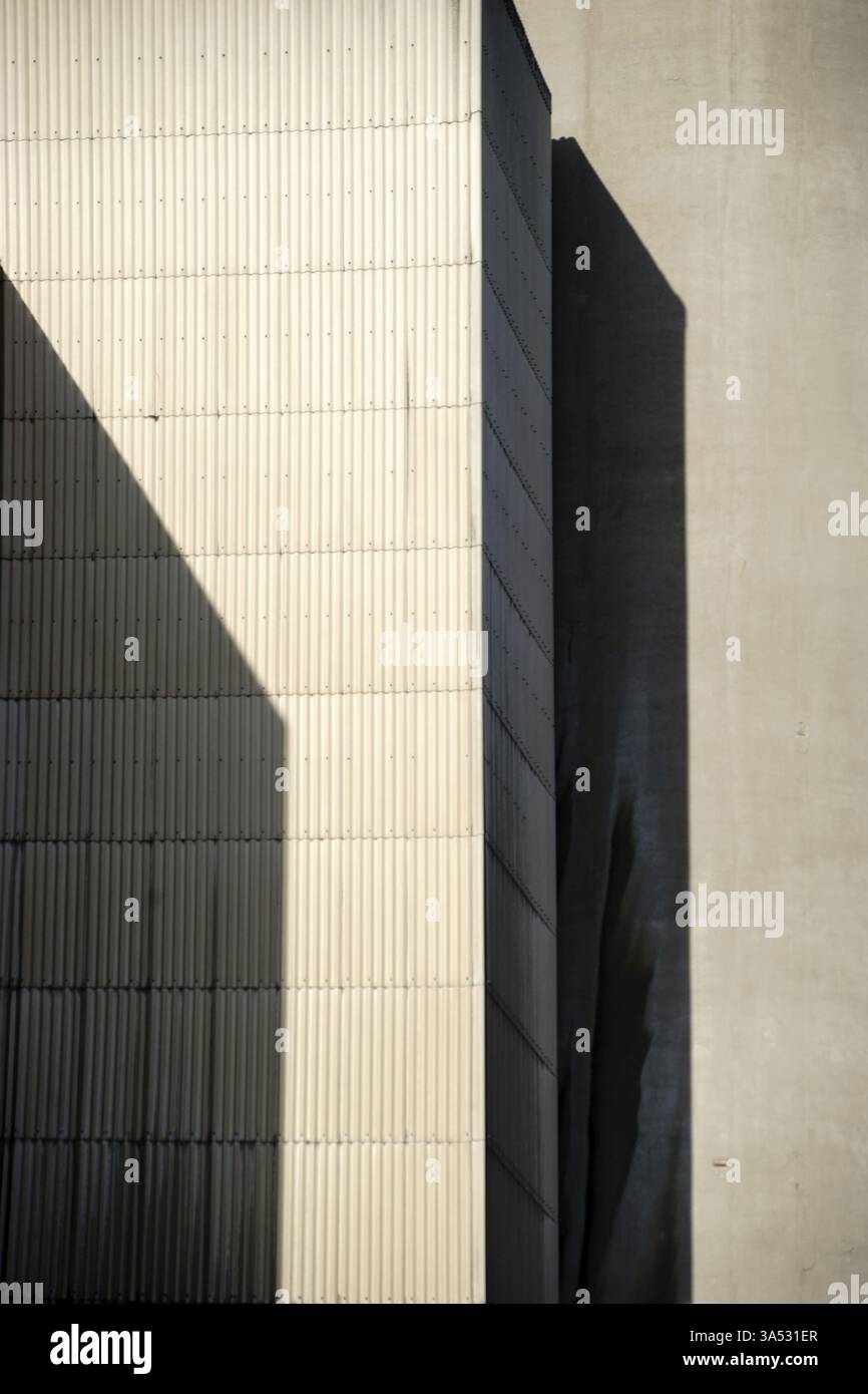Gli angoli e i bordi di un edificio industriale proiettano ombre geometriche Foto Stock