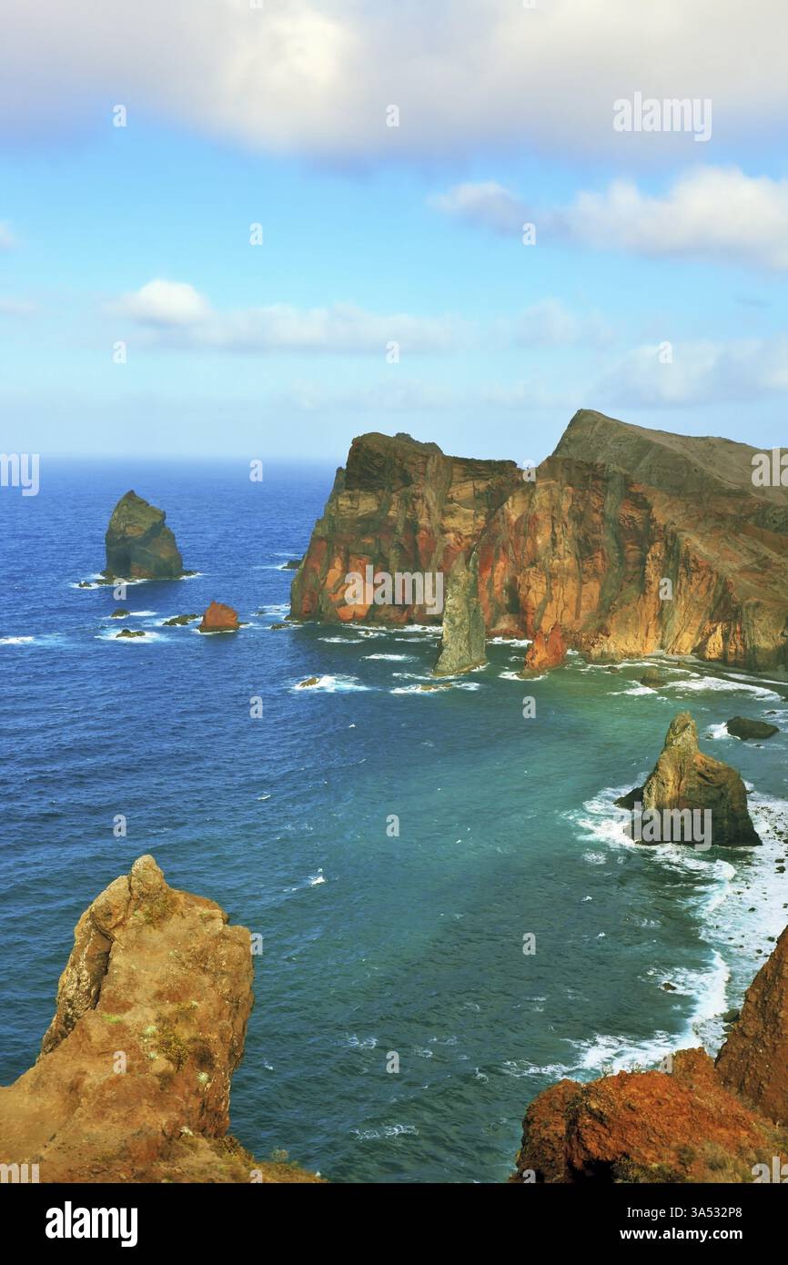Punta orientale dell'isola di Madeira. Le rocce rosse e arancioni fresche crescono dalle onde smeraldo dell'Oceano Atlantico Foto Stock