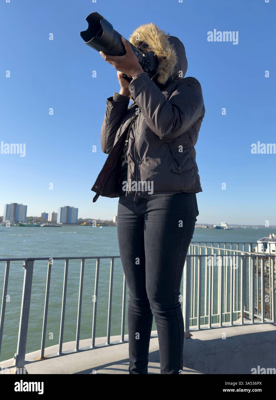 Portsmouth, Inghilterra, Regno Unito. 18.03.2025. Donna che utilizza una costosa fotocamera con obiettivo lungo per scattare foto nel porto di Portsmouth, Regno Unito. Foto Stock
