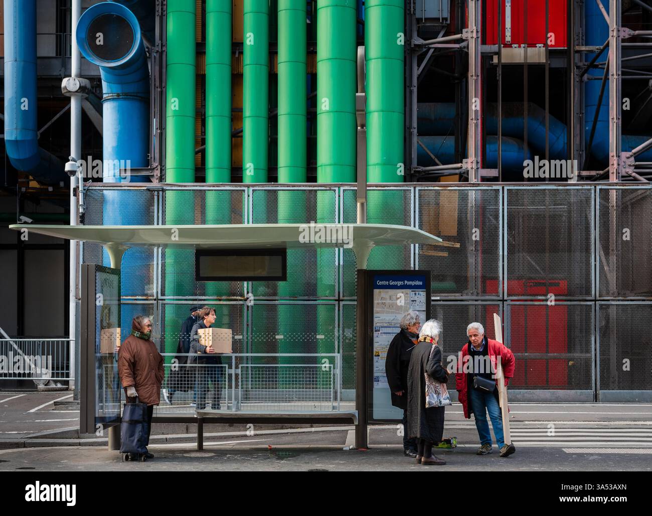 Persone in attesa alla fermata dell'autobus di fronte al Centre Pompidou a Parigi, Francia. Le tubature colorate sono una delle caratteristiche architettoniche. Foto Stock