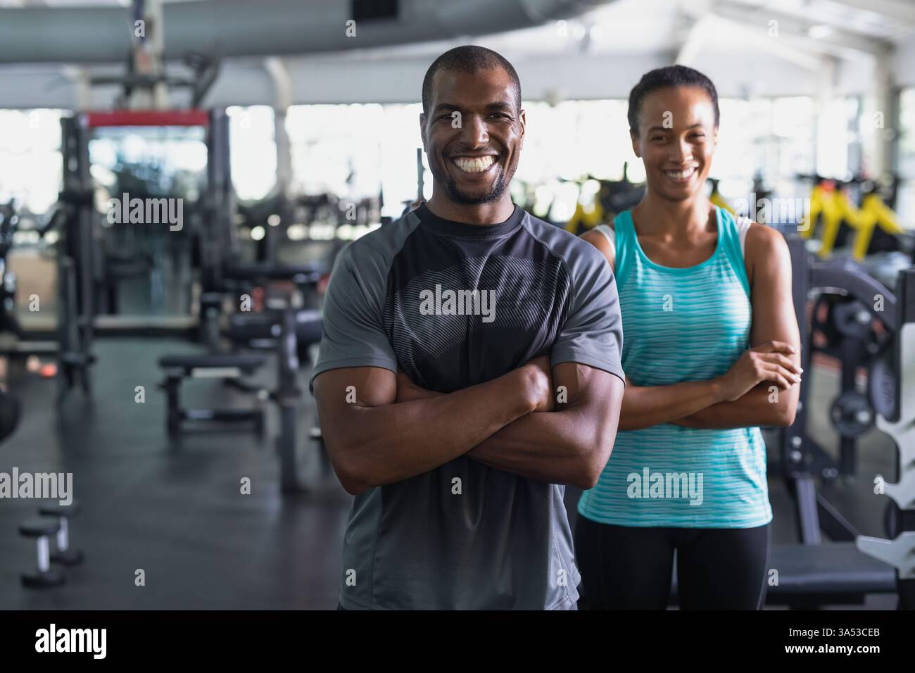 Atleti sorridenti in piedi in tutta sicurezza nella moderna palestra, pronti per le sessioni di allenamento Foto Stock