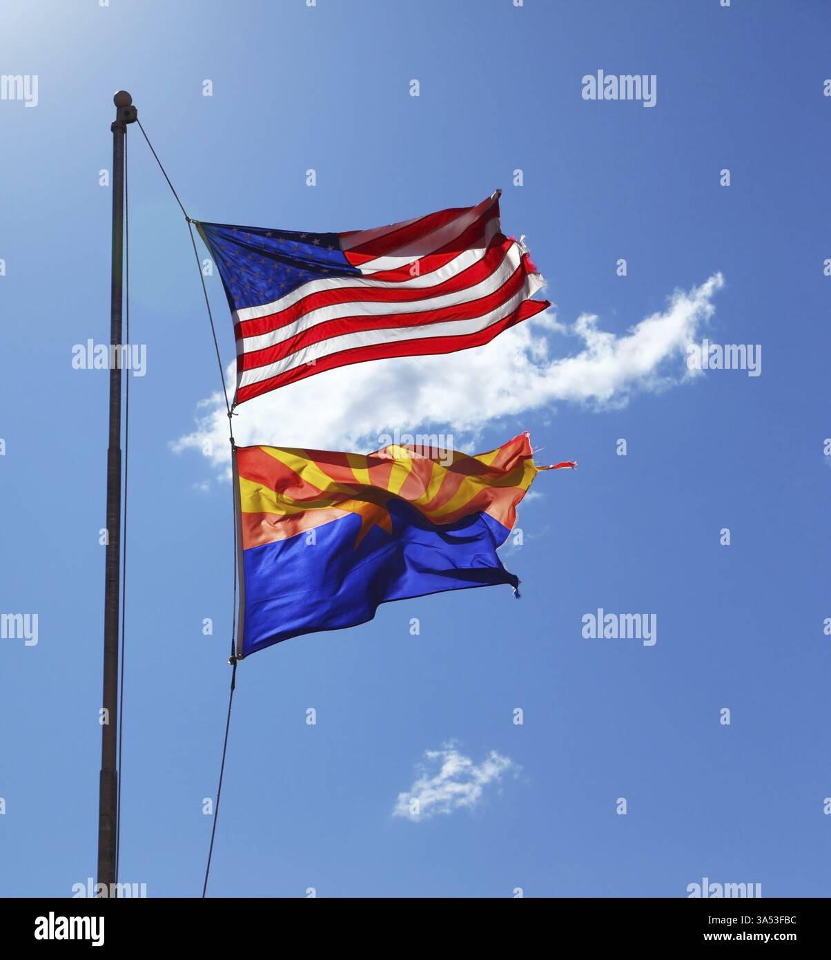 Le bandiere degli Stati Uniti e della riserva Navajo stanno volando contro il sole splendente e le nuvole Foto Stock