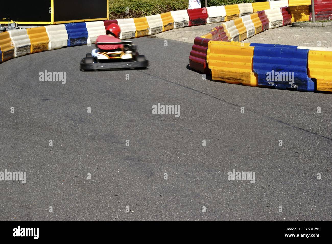 Un pilota di kart attraversa la curva su una pista di kart limitata Foto Stock