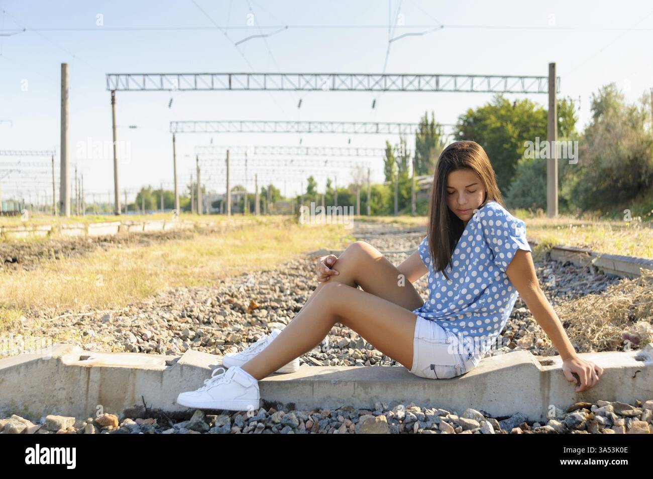 Bruna adolescente seduta sul cemento di una ferrovia incompiuta fuori città Foto Stock