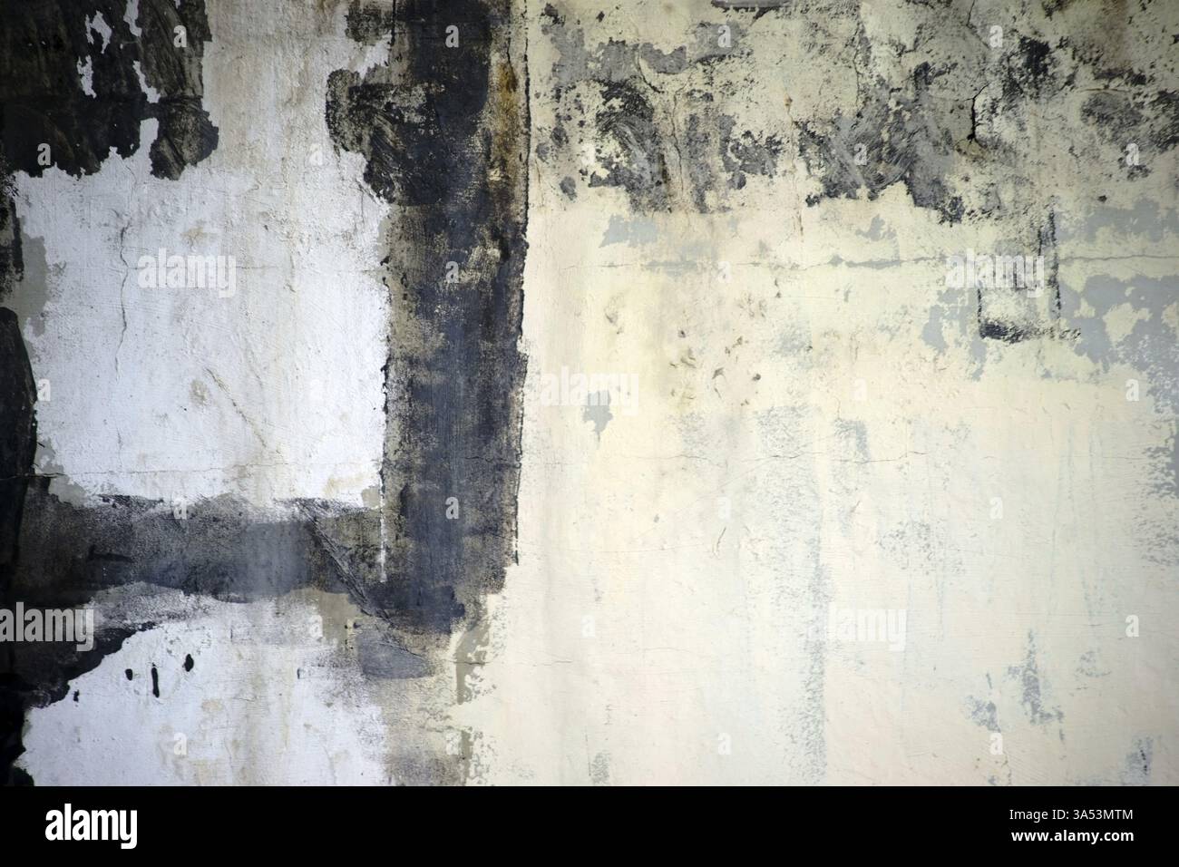 Primo piano di una parete di colore chiaro con tratti di vernice nera e macchie colorate Foto Stock