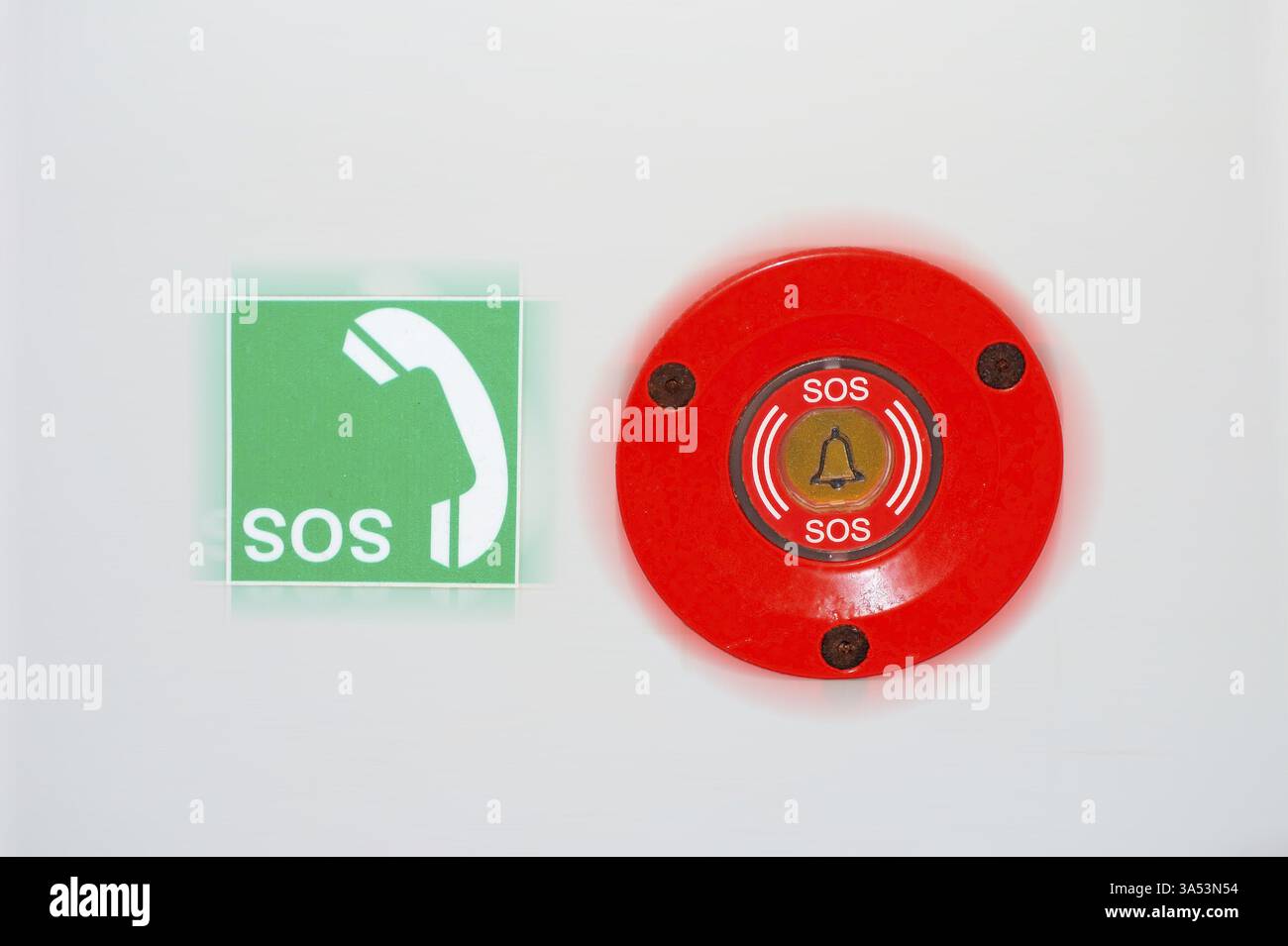 Un interruttore di emergenza e un adesivo con il cartello SOS con un ricevitore telefonico sulla parete di un WC per disabili Foto Stock