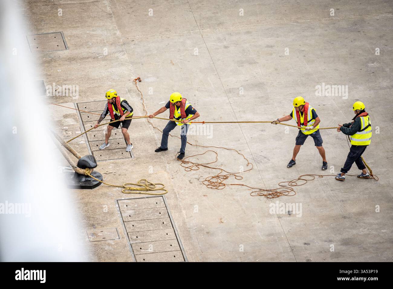 Testa di lavoratori portuali che trasportano una nave da crociera nel porto. Lisbona sta attuando il progetto di fornitura di energia elettrica a terra alle sue navi. Foto Stock
