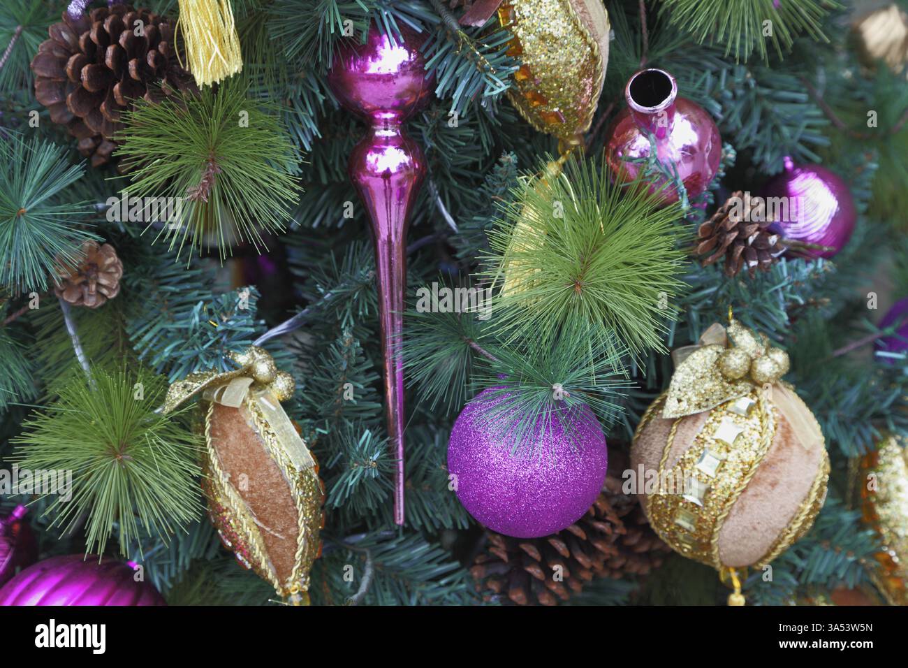 Sfere rosa e gialle, fiocchi di neve decorativi, picchi di vetro e figure di fantastici eroi decorano un tripudio di Capodanno. Buon Natale! Foto Stock