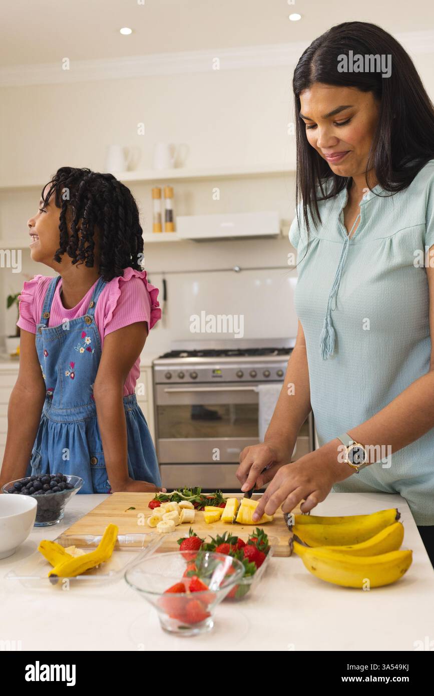 Mamma e figlia preparano l'insalata di frutta insieme in cucina, godendosi il tempo libero in famiglia Foto Stock
