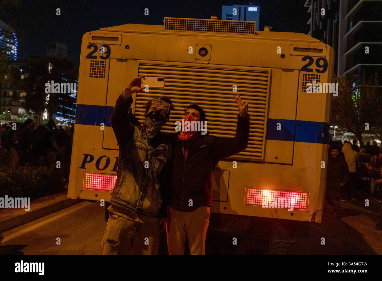 I manifestanti con i loro volti coperti scattano selfie davanti a un'auto della polizia durante una protesta a sostegno di Ekrem Imamoglu. I manifestanti si sono riuniti per sostenere Ekrem mamo lu e opporsi alla sua detenzione. Il popolo voleva marciare verso l'edificio provinciale del partito AK, il partito del presidente turco Recep Tayyip Erdogan, ma la polizia intervenne con gas lacrimogeni e cannoni ad acqua. Imamoglu, sindaco del Partito Popolare Repubblicano (CHP) di Istanbul, è stato arrestato insieme a dozzine di suoi aiutanti e membri del partito con l'accusa di corruzione e guida di un'organizzazione criminale. Definire l'arresto una cospira politica Foto Stock