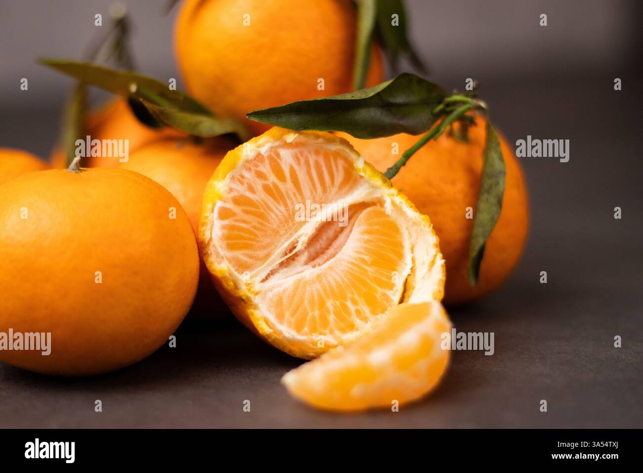 Primo piano di fette di mandarino sbucciate e amalgamare interi mandarini sullo sfondo del tavolo Foto Stock