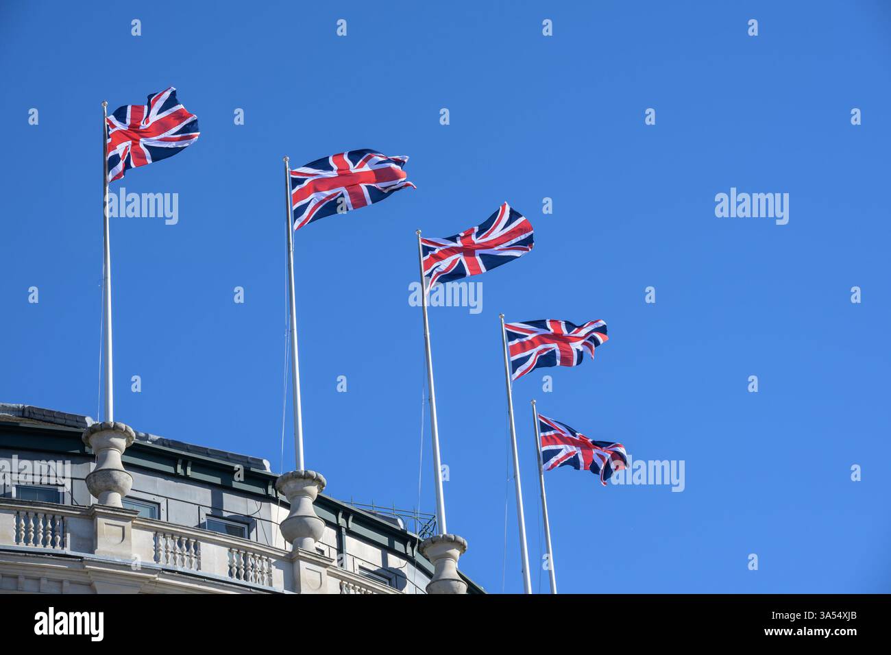 Londra, Regno Unito. Bandiere dell'Unione che sventolano dal tetto del "Grand Building" all'angolo tra Strand e Trafalgar Square Foto Stock