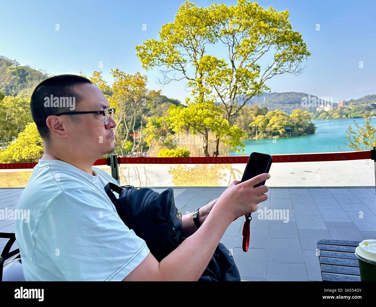 Yuchi, Taiwan, turista cinese, guarda il profilo del telefono, visita l'area turistica panoramica "Lago Sole Luna", est di Taiwan, - Immagine stock catturata con smartphone