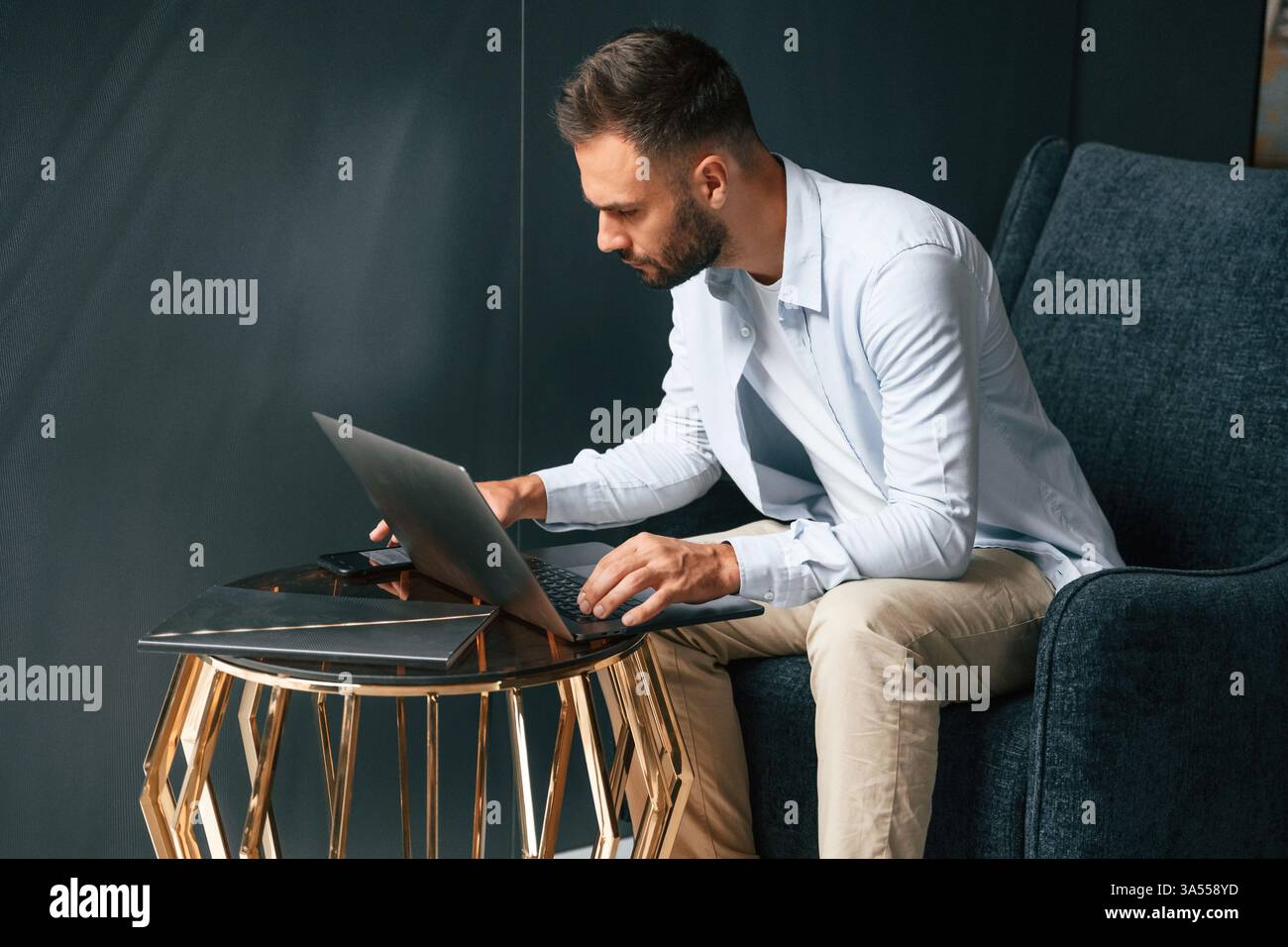 Concentrato, sicuro di sé. L'uomo d'affari è seduto e lavora utilizzando un computer portatile. Foto Stock