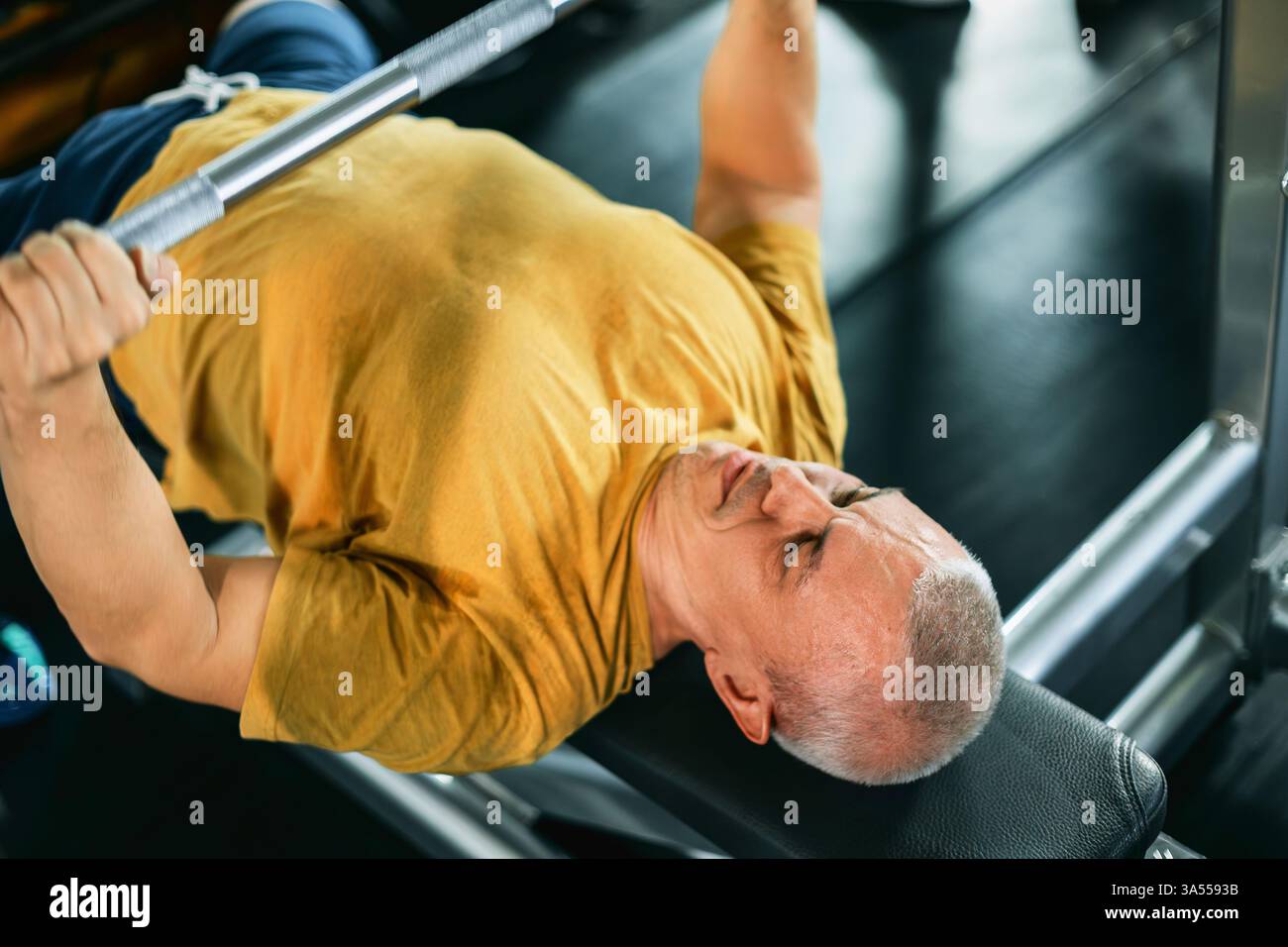 Uomo muscoloso che esegue una pressa da banco in palestra Foto Stock