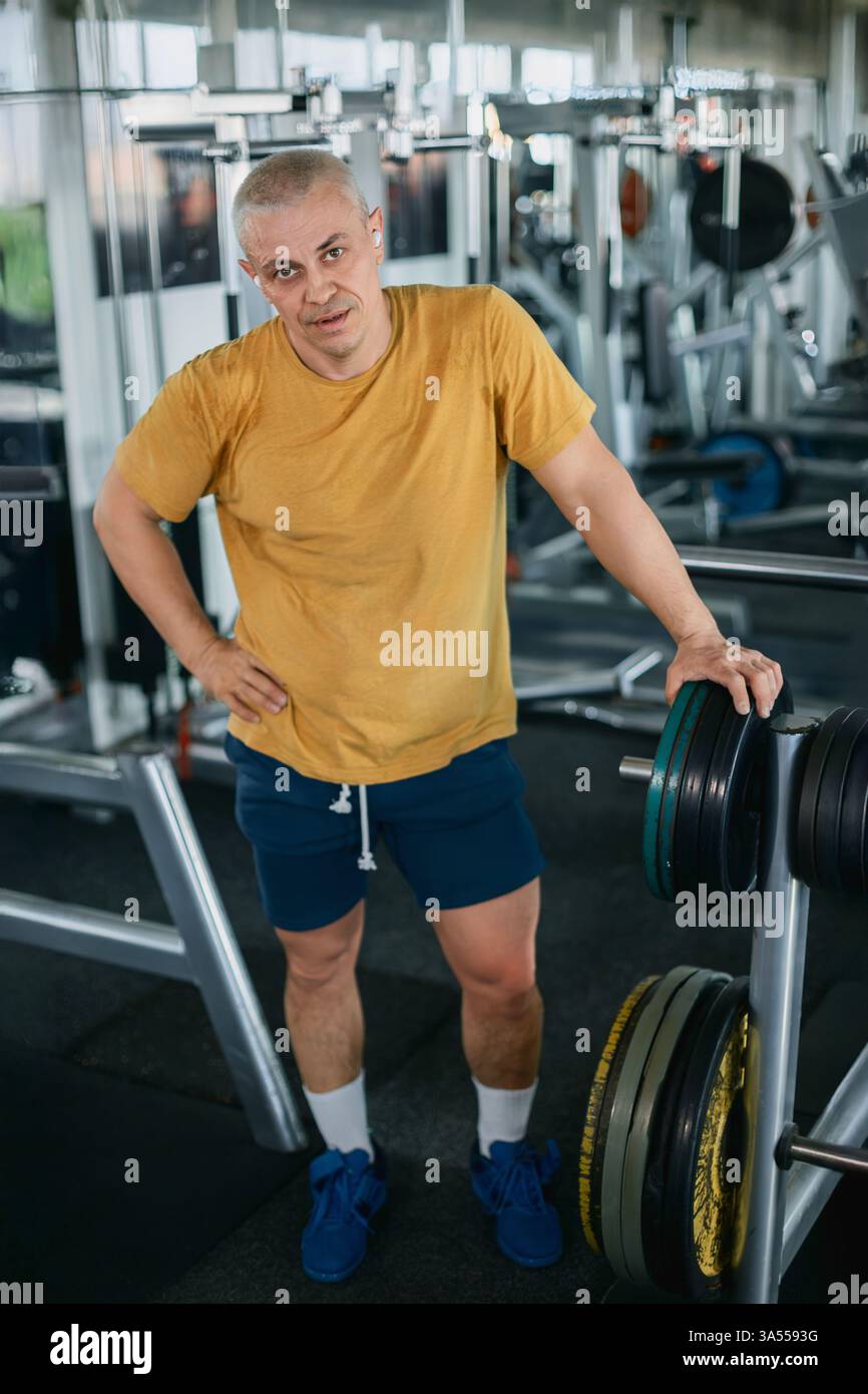 Uomo muscoloso che riposa dopo un allenamento in palestra Foto Stock