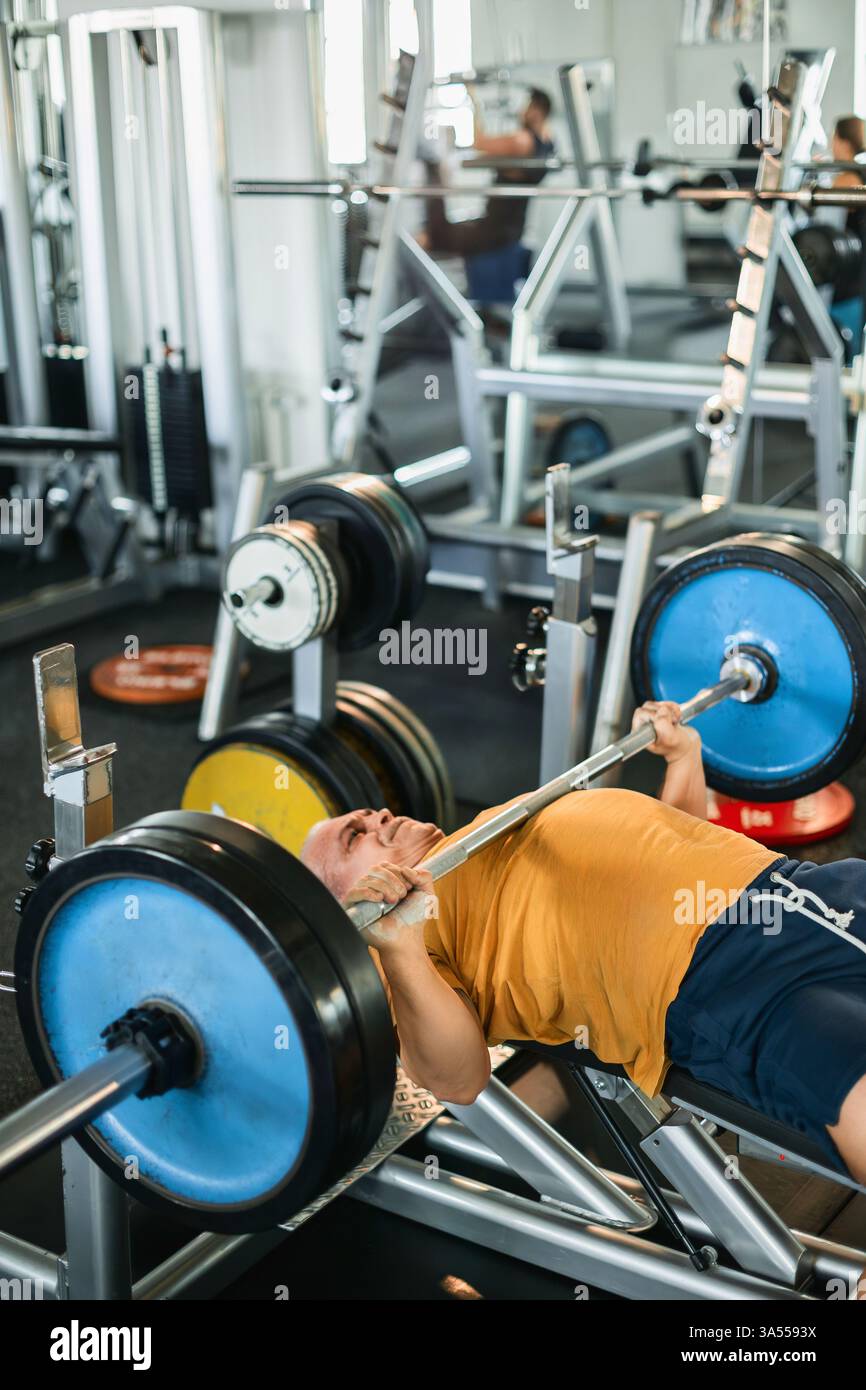 Atleta che fa potenti panchine in palestra Foto Stock
