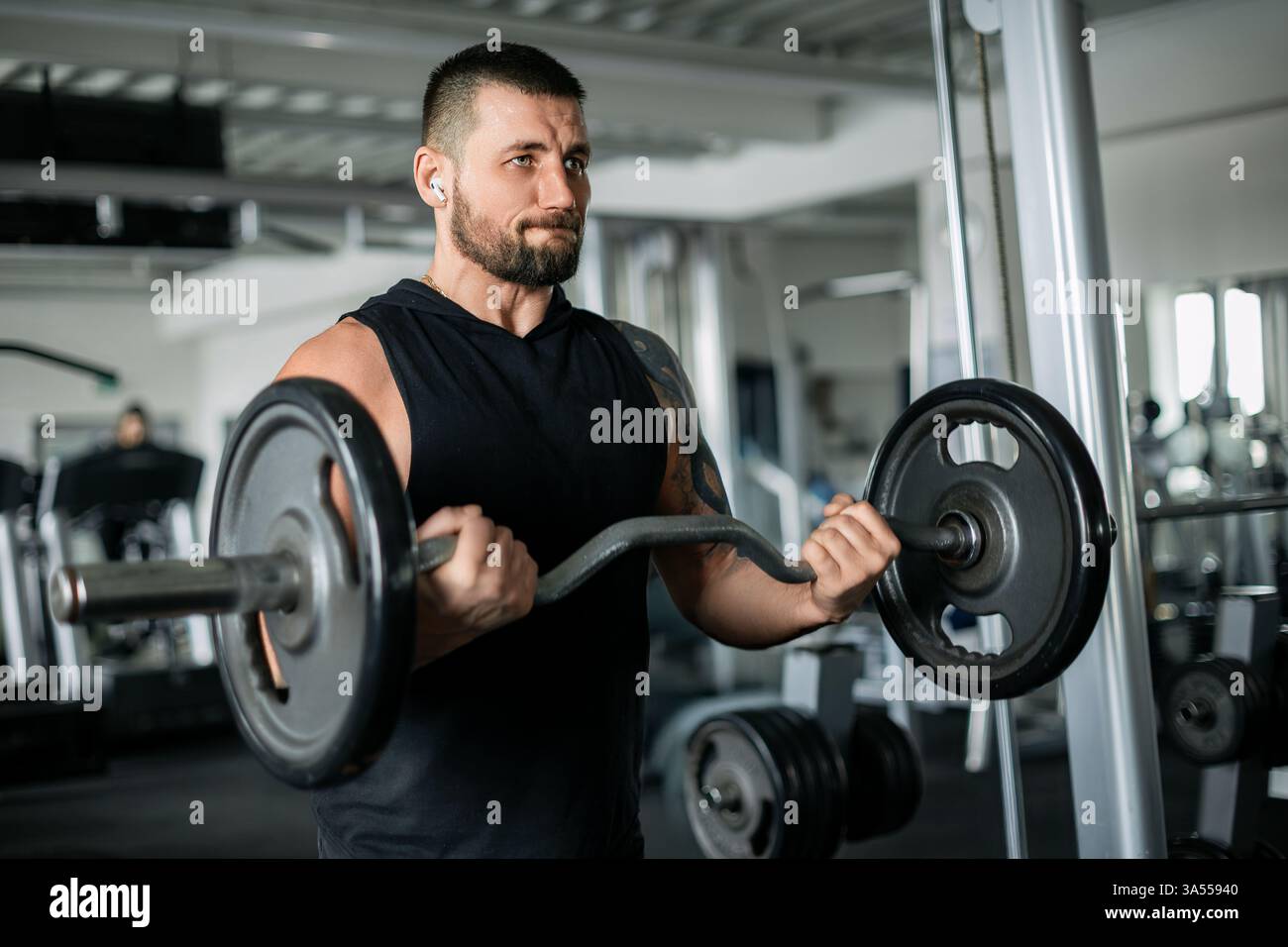 Uomo concentrato che solleva un barbell durante un intenso allenamento in palestra Foto Stock