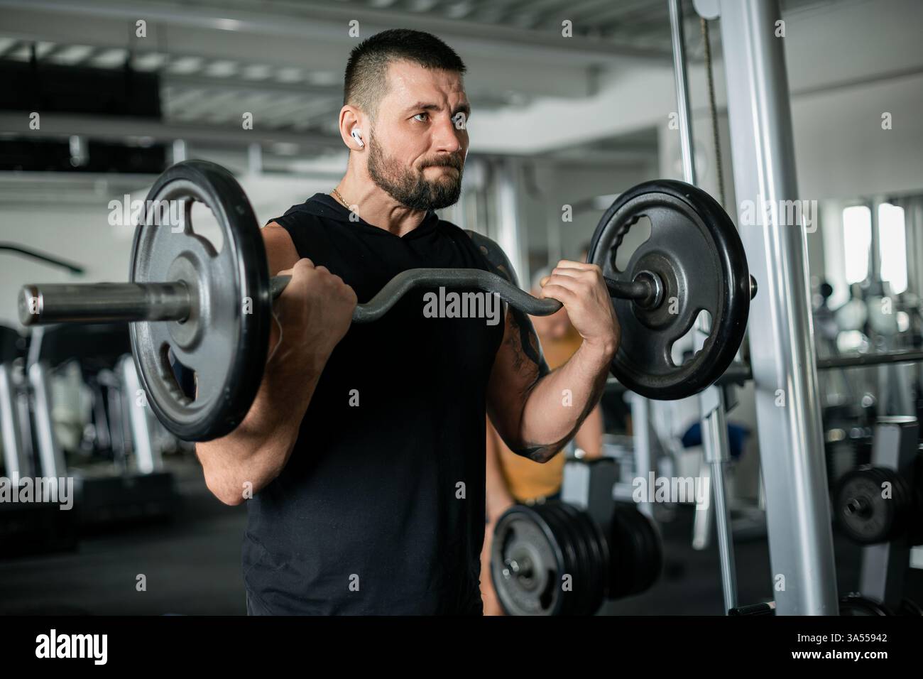 Uomo determinato che solleva un barbell in un allenamento in palestra Foto Stock