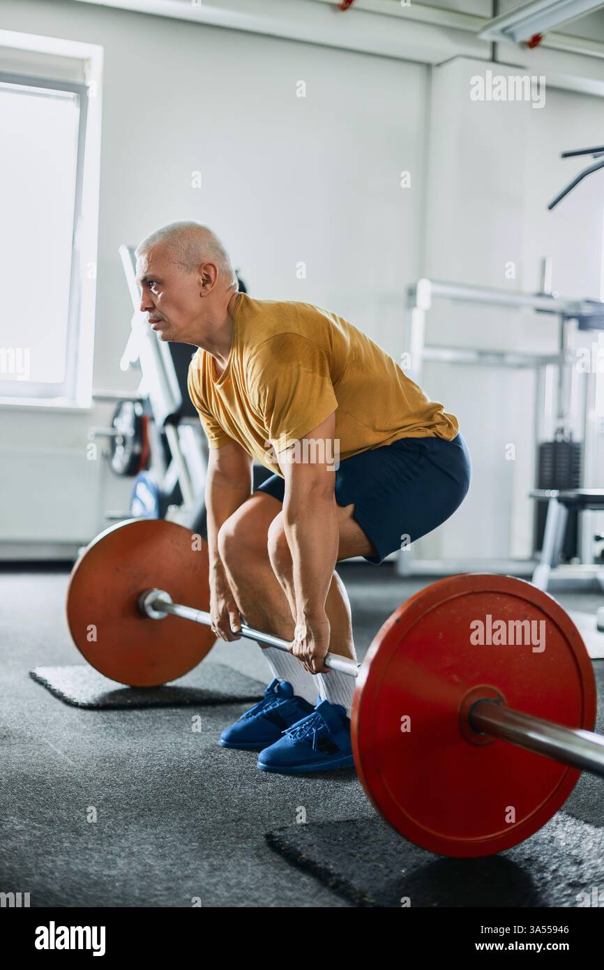 Uomo che esegue un esercizio di deadlift con il barbell in palestra Foto Stock