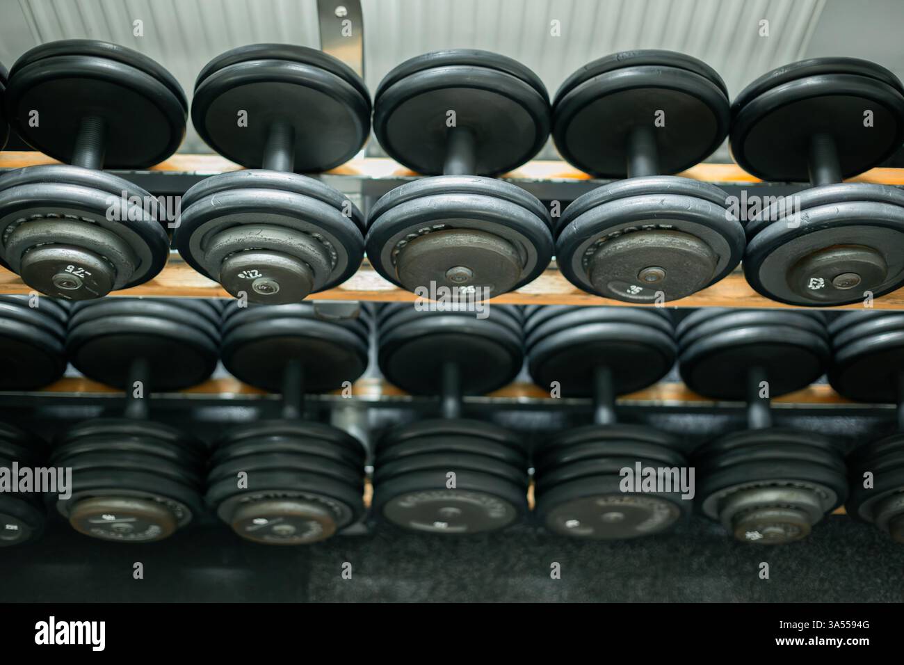 Set di manubri neri disposti in modo ordinato su un rack da palestra Foto Stock