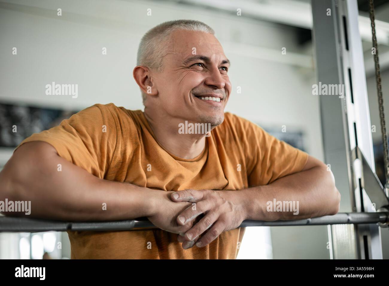 Uomo sorridente che riposa dopo un allenamento in palestra Foto Stock