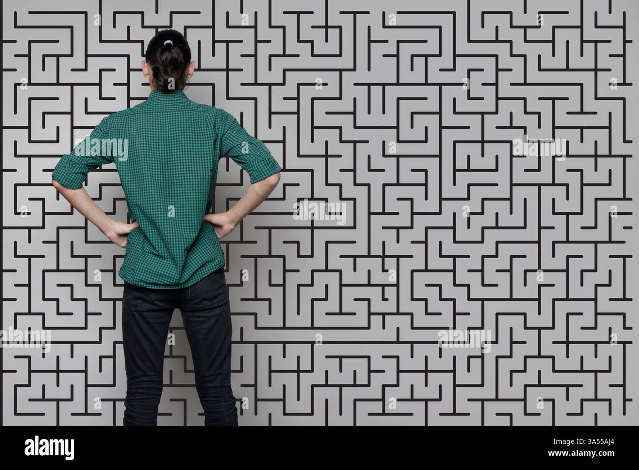 Una donna è in piedi vicino a un muro con un disegno di un labirinto. Concetto di brainstorming, pensiero, risoluzione dei problemi Foto Stock