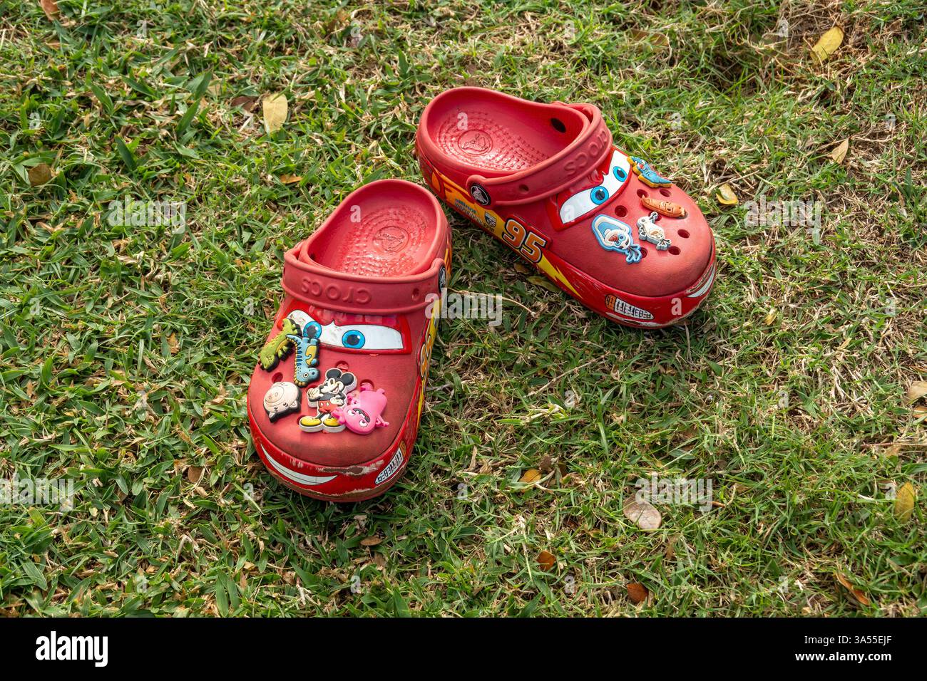 Disney Pixar Red Lightning McQueen Crocs Clogs Shoes Left Behind on A Grass Field, Stock Photo Foto Stock