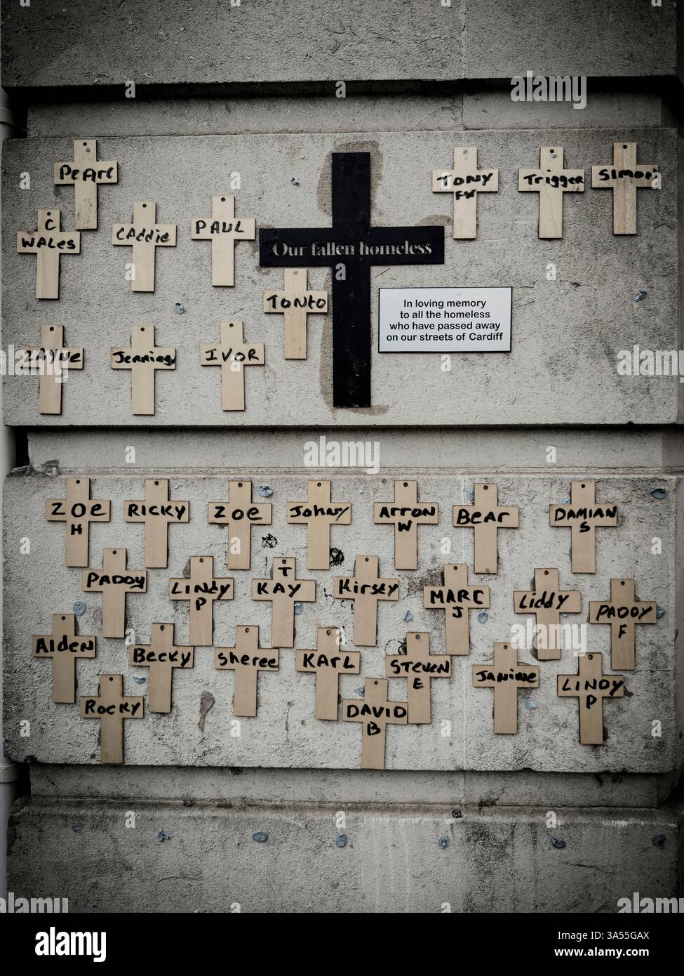 Una solenne esposizione di crocifissi adorna il muro, ognuno un silenzioso tributo alle anime dei senzatetto caduti di Cardiff: Phillip Roberts - Immagine stock catturata con smartphone