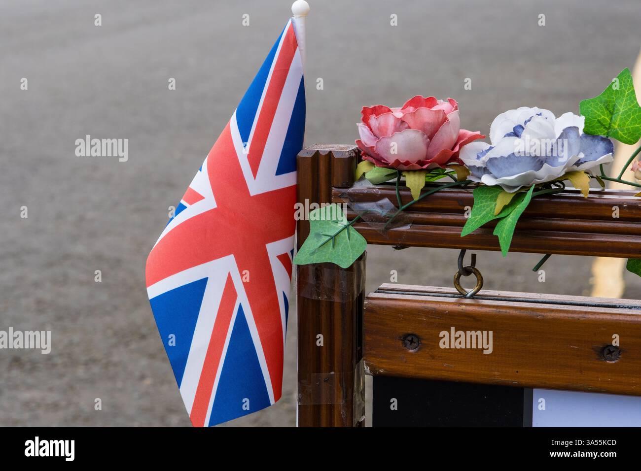 Su una strada con bandiera union Jack e decorazioni di fiori di plastica Foto Stock