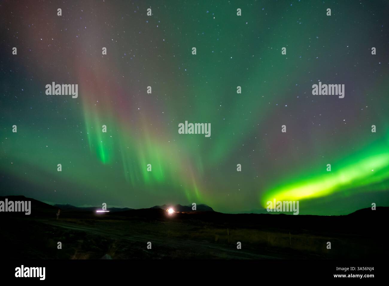 L'aurora boreale mozzafiato in Islanda, l'aurora boreale verde e viola che illuminano un cielo stellato cristallino con onde di luce ipnotiche Foto Stock