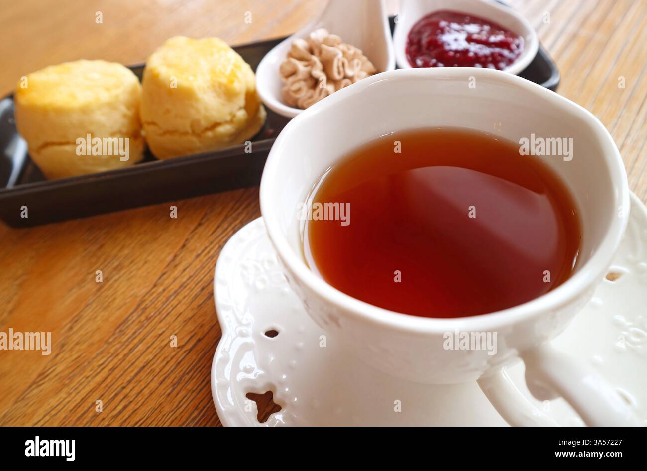 Primo piano di tazze di tè caldo con piatto di focaccine sullo sfondo Foto Stock