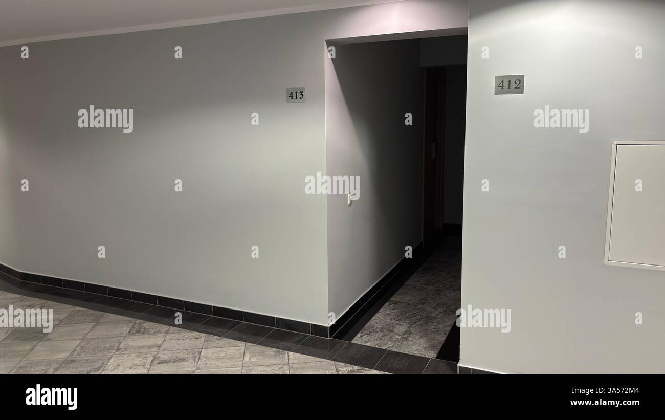 interno di un hotel. Corridoio scuro che conduce ad una camera d'albergo. Pavimento piastrellato e pareti vuote sterili - Immagine stock catturata con smartphone