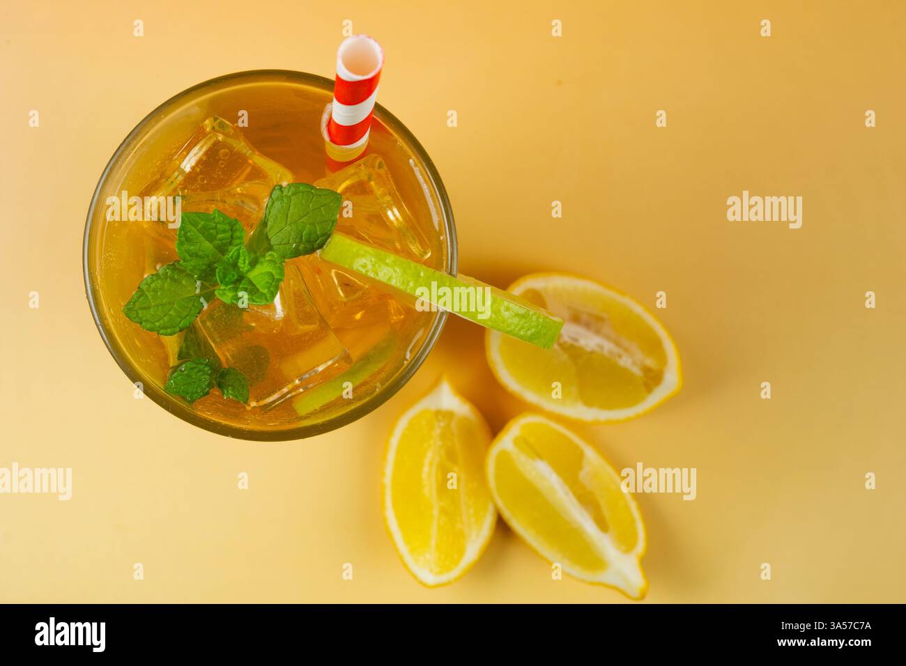 Un bicchiere di tè ghiacciato con fette di lime e limone. La bevanda è servita in un bicchiere con foglie di menta sulla parte superiore e paglia. Vista dall'alto Foto Stock