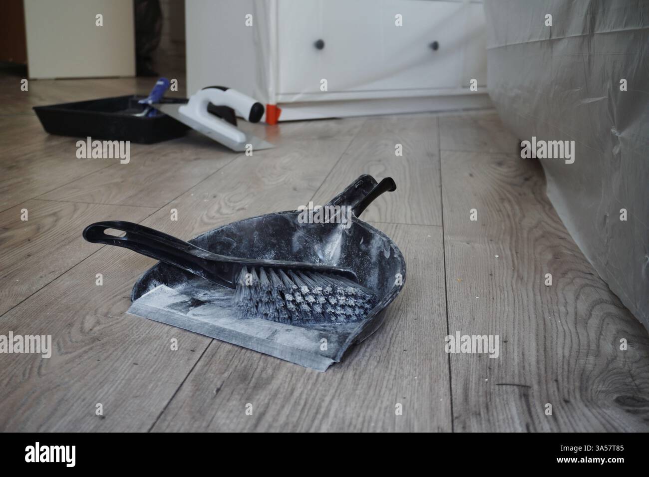 ristrutturazione, arredi coperti con plastica. Ridecorazione di appartamenti e costruzione di case, pulizia di polvere bianca. paletta e scopa Foto Stock