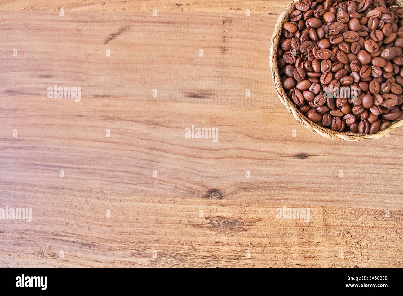 Cestello in tessuto riempito con chicchi di caffè tostati su una superficie di legno. Tonalità calde e rustiche, ideali per caffè, caffè o sfondi di cibo naturale. Foto Stock