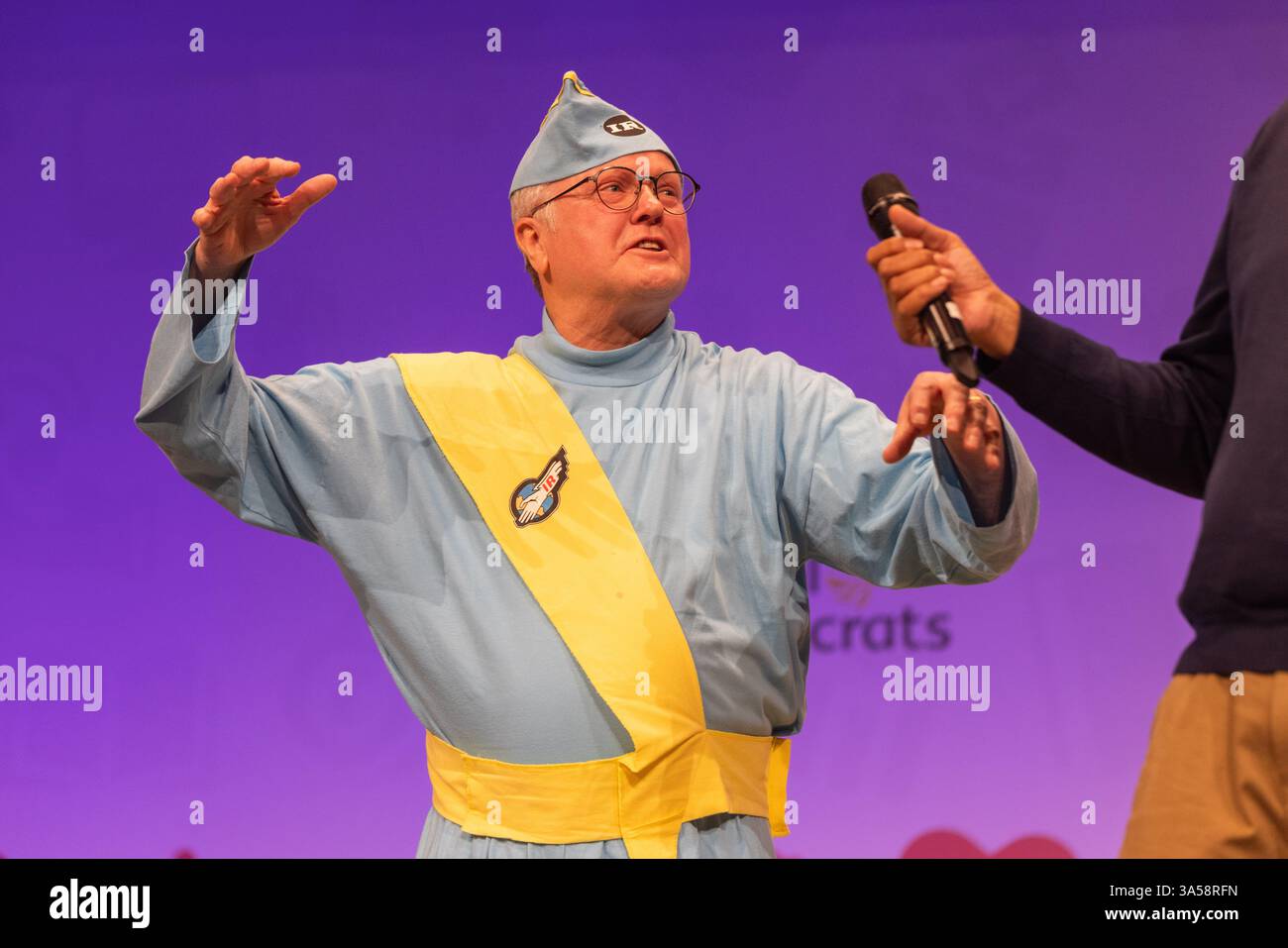 Harrogate, Regno Unito. 21 MARZO 2025. Il deputato Clive Jones, membro dei Liberal Democratici per Wokingham arriva sul palco vestito da Thunderbird il primo giorno della conferenza di primavera dei Liberal Democratici presso l'Harrogate Exhibition Centre nello Yorkshire. Credito Milo Chandler/Alamy Live News Foto Stock