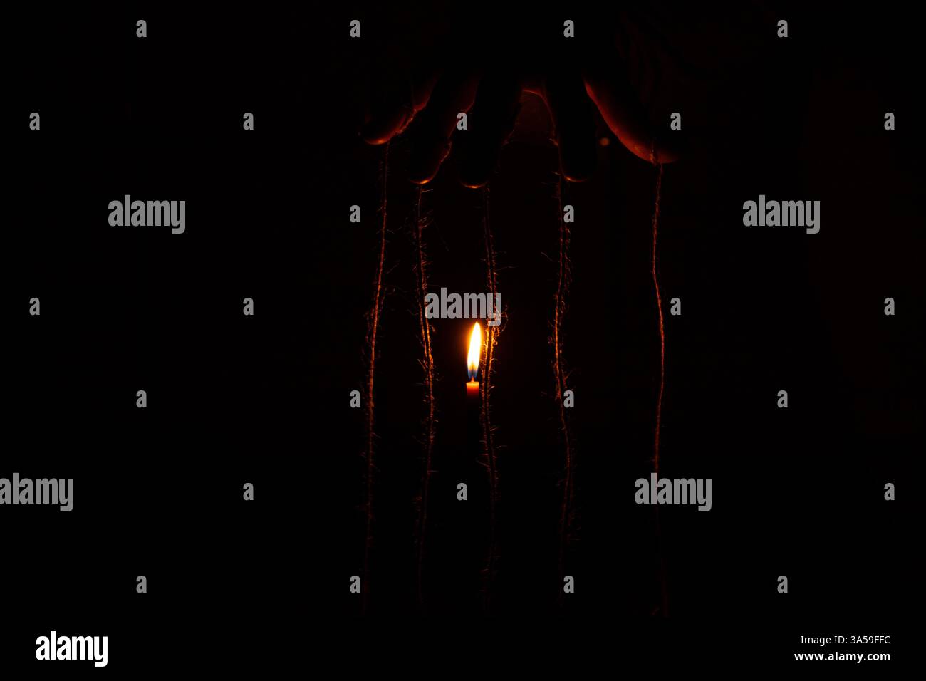 Mano femminile con corde sulle dita al buio vicino a candela, burattinaio, controllo sulle persone, forza le mani Foto Stock
