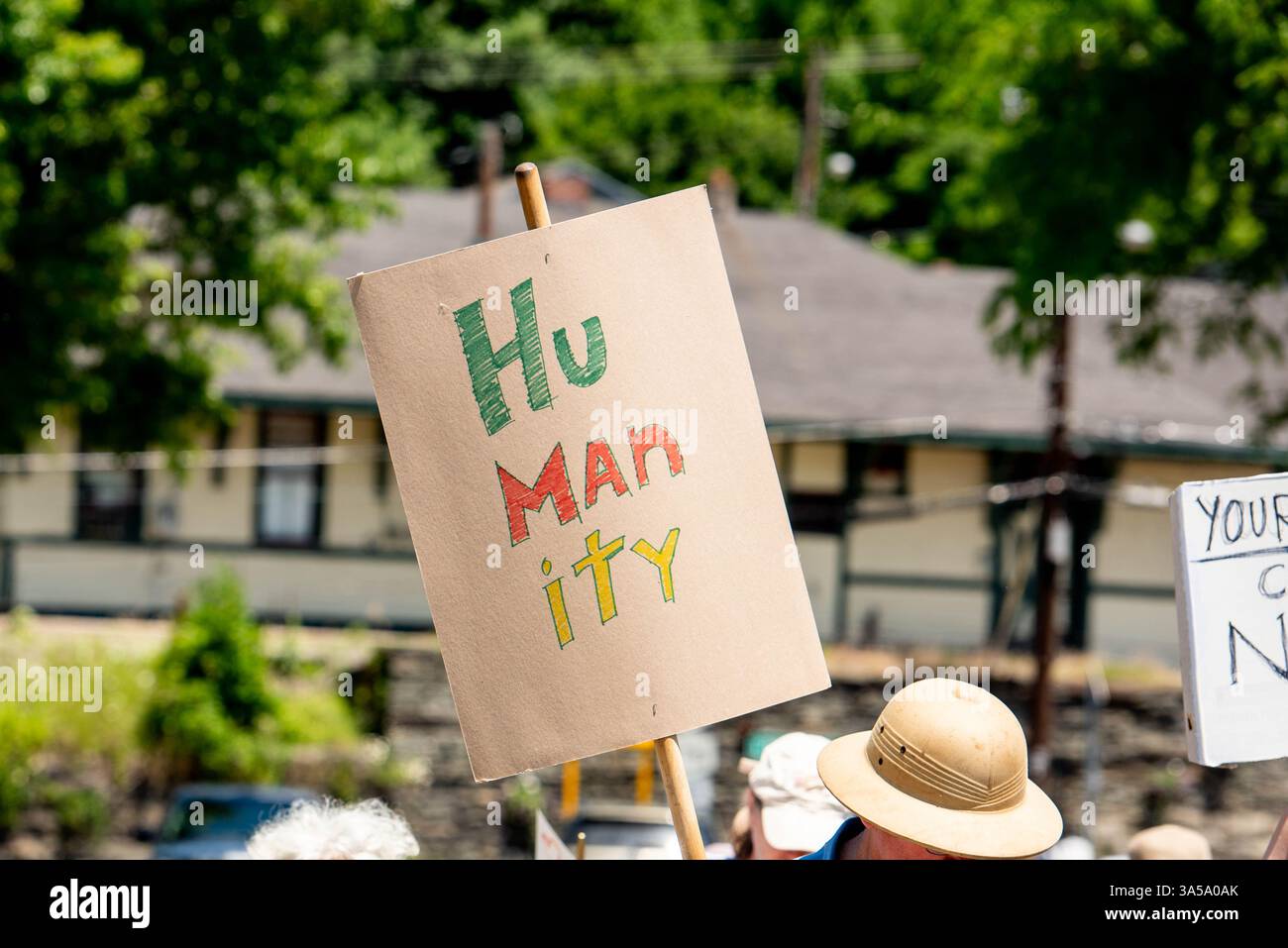 Un attivista di una manifestazione di protesta politica e di marcia ha un segno che recita "umanità" con scritte scritte colorate a mano. Foto Stock