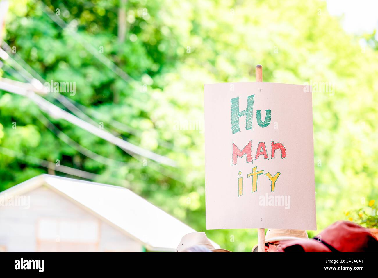 Un attivista di una manifestazione di protesta politica e di marcia ha un segno che recita "umanità" con scritte scritte colorate a mano. Foto Stock